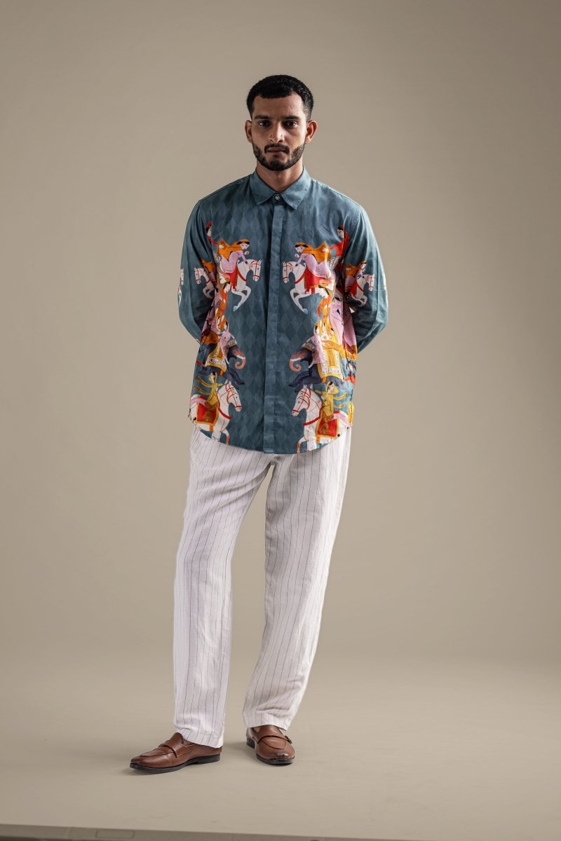 Man wearing the Kirtharjuna shirt with white trousers, full length front view, hands behind his back