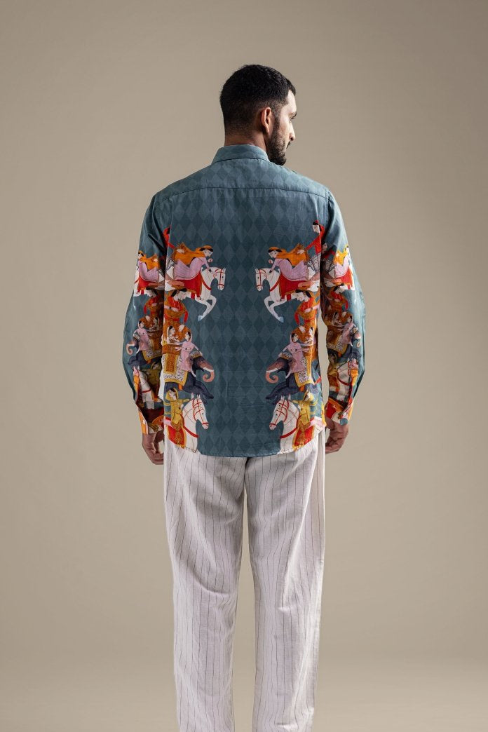 Man wearing the blue Kirtharjuna shirt, back view showing the procession artwork