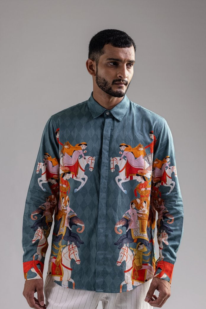 Man wearing the blue Kirtharjuna shirt, waist-up front view, looking at the camera