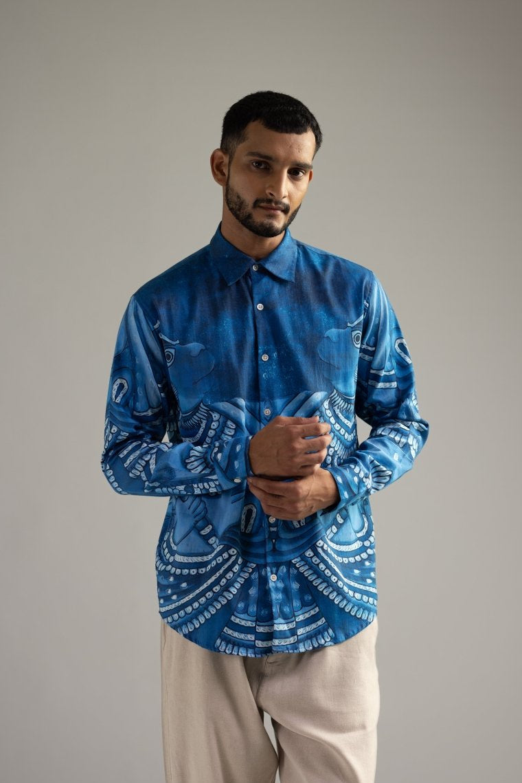 Man wearing the indigo blue Vanaryugalam shirt, front view, hands clasped