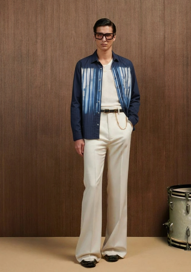 Man wearing a blue and white striped shirt with white pants against a wooden background